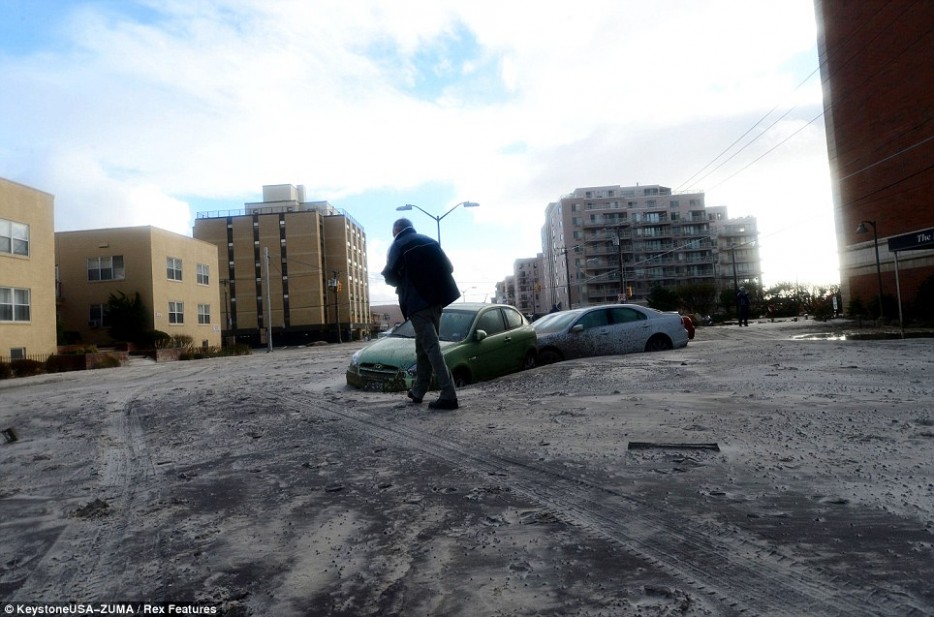 A pedestrian walks through sand-covered, abandoned streets in the aftermath of hurricane Sandy