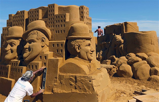 A sand carver works on a sculpture during the Sand Sculpture Festival in Ostend, Belgium, June 23, 2014. A team of 33 carvers from around the world spent five weeks building giant sculptures based on the ''Disneyland Paris Sand Magic'' theme. Nearly seven tons of sand were needed to complete 150 sculptures.
