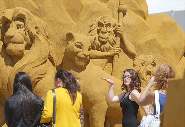 Visitors pose and take photographs of sand sculptures on the beach at the North Sea town of Ostend, Belgium on Sunday, June 29, 2014. Artists from around the world created a fantasy world based on the characters of Disneyland.