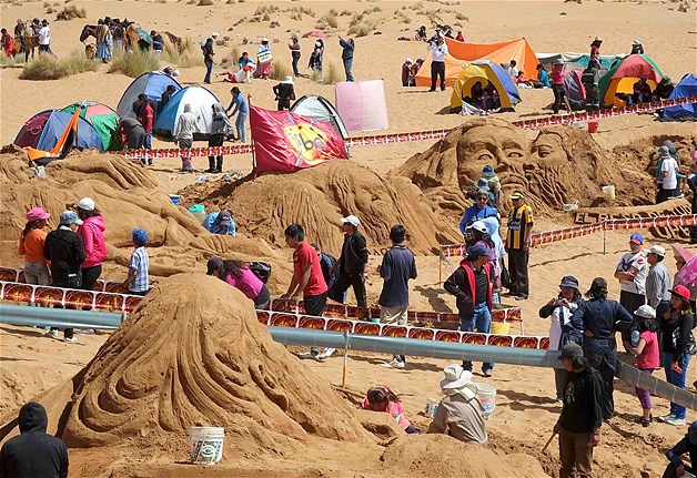Artists rest next to a sand sculpture depicting Matthew writing the gospel during Holy Week celebrations in Arenal de Cochiraya, on the outskirts of Oruro, Bolivia, April 18, 2014. Hundreds of artists and art students gathered for the annual Good Friday event, building sand sculptures based on Bible stories.