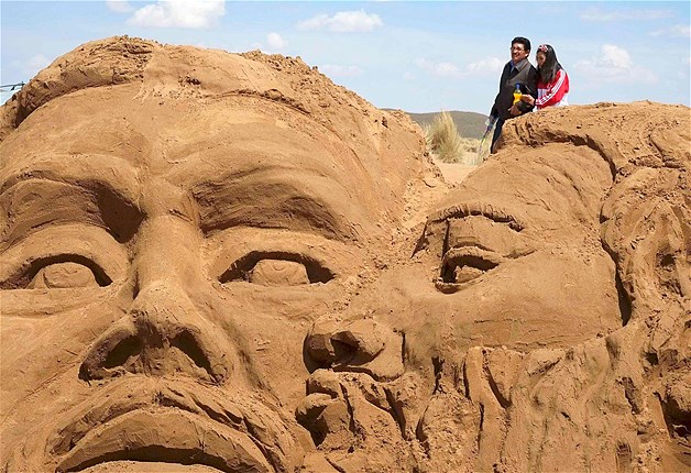 A couple walks near a sand sculpture that depicts the scene of "The Kiss of Judas" during Holy Week celebrations in Arenal de Cochiraya, on the outskirts of Oruro, Bolivia, April 18, 2014. Hundreds of artists and art students gathered for the annual Good Friday event, building sand sculptures based on Bible stories.