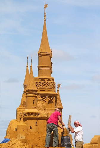 Artists work on their art pieces during the sand sculpture festival at the Northsea town of Ostend, Belgium, June 29, 2014. Artists from around the world created a fantasy world based on the characters of Disneyland.