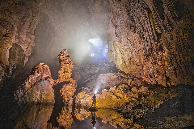 A torch-wielding man casts a tiny shadow as he stands in the vastness of the world's biggest cave, the Hang Son Doong cave in Vietnam.