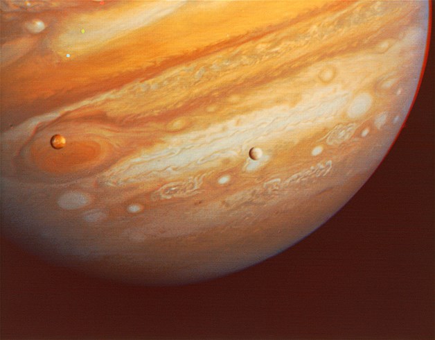 Jupiter as seen by Voyager 1 at a distance of more than 28.4 million kilometers, or 17.5 million miles. The white moon to the right is Europa, and the red moon to the left is Io.