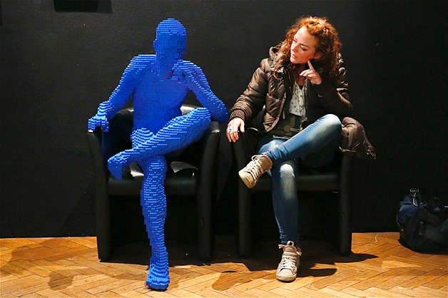 A visitor poses beside art work titled "Blue Guy Sitting" made out of Lego bricks during the "The Art of the Brick" exhibition at the Brussels Stock Exchange in Belgium on Nov. 25, 2013. The exhibition featured large Lego art works by New York Lego artist Nathan Sawaya.