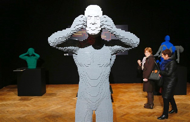 Visitors walk behind the art work titled "Mask" constructed out of 18,509 Lego bricks during "The Art of the Brick" exhibition at the Brussels Stock Exchange in Belgium, Nov. 25, 2013. The exhibition featured large Lego art works by New York Lego artist Nathan Sawaya.