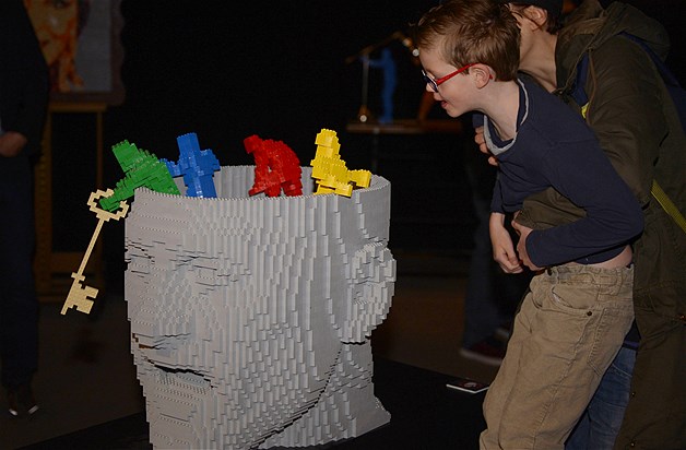 A boy gets a little help from his dad to see a Lego sculpture from New York artist Nathan Sawaya at "The Art of the Bricks" exhibition in Brussels, Belgium, April 18, 2014.