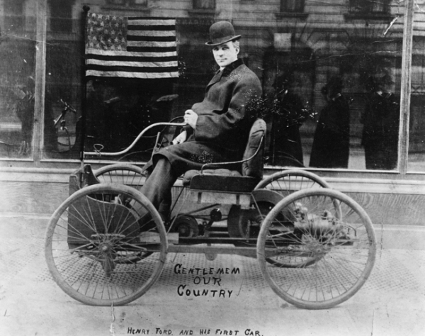 Henry Ford poses on the first car he built, the Ford Quadricycle. 1896