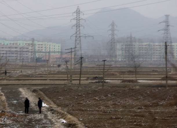 Entire country suffers from chronic power outage. Residences, offices usually receive electricity for only a few hours in a day. Pictured People walk through a field scattered with electricity poles in the North Korean capital of Pyongyang.