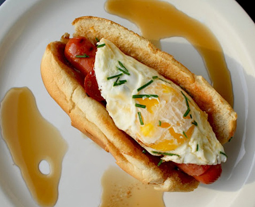Breakfast Dog: A fried egg, sprinkled cheddar cheese and chives on top of a hot dog wrapped in turkey bacon, with cinnamon and sugar butter and maple syrup.
