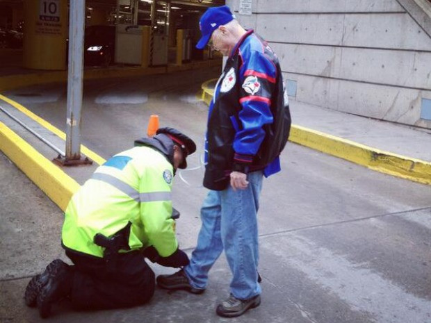 This police officer tied the shoelaces of an old man.