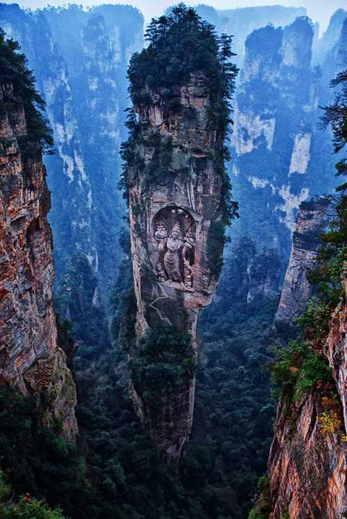 Here's another place that looks too amazing to be real...because it is. The rock formation is real, and is located in the Tianzi Mountain Nature Reserve in China. The sculpture was added later.