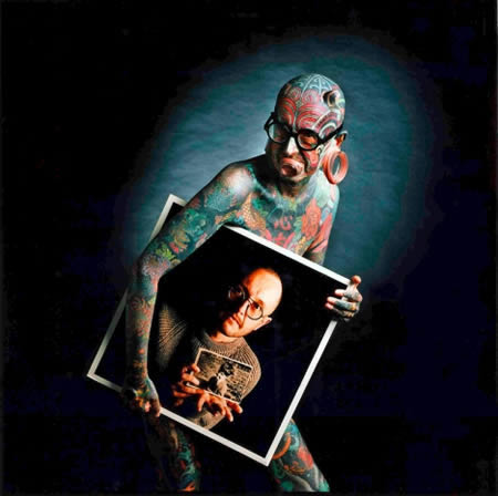 Etienne Dumont: Living art: Etienne Dumont is an art & culture critic for a newspaper in Geneva who just happens to be covered head to toe in some of the most vibrant tattoos ever mande. He also has silicon implants under the skin which give the horned appearance, 2.7 inch rings in each earlobe and plexiglass piercings through the nose and under his bottom lip. And he claims to wear his tattoos like art.