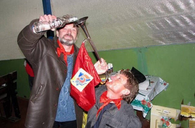 pouring alcohol through an instrument into a persons mouth