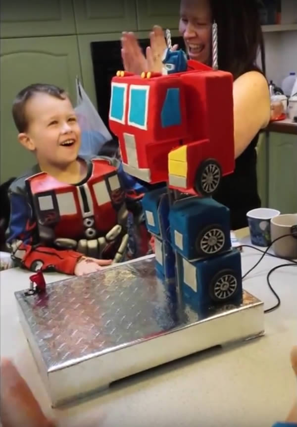 Stop what you are doing, you are about to see the coolest cake ever. A boy asked for a Transformers cake for his 6th birthday, so his mom made the actual cake, and his dad added something unbelievable to give it that Transformer's vibe.

The kid's dad came up with a platform that would move the cake up in levels and give the illusion of Optimus Prime's transformation from vehicle mode to robot mode.