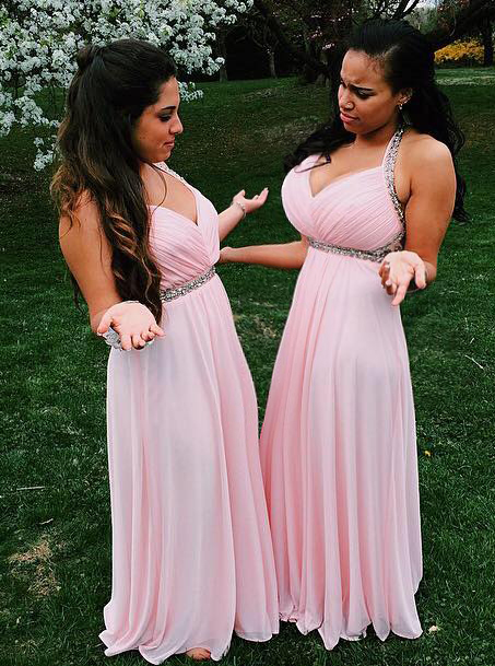 Two bridesmaids in pink dresses looking at each others breasts