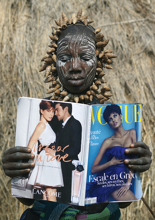 A woman of the Mursi tribe of the Ethiopian Omo Valley thumbs through an issue of Vogue