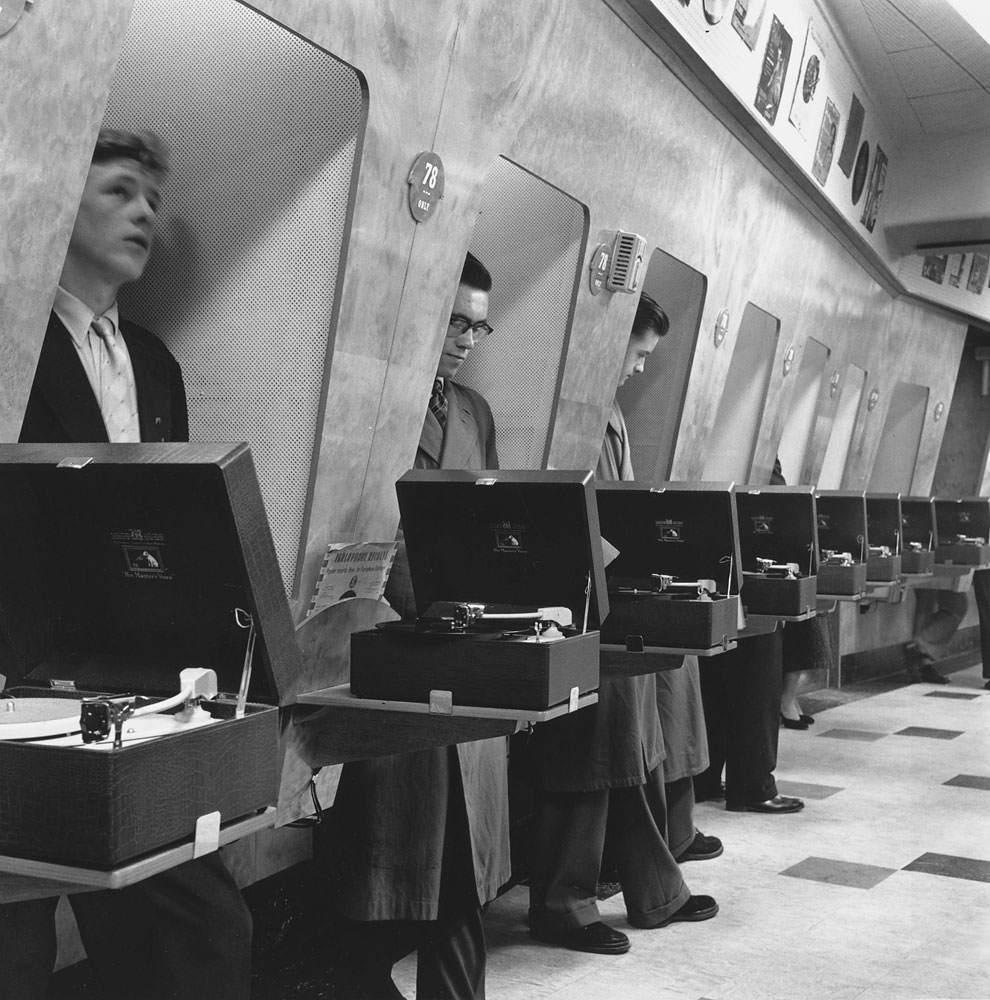 Customers at a London music store listen to the latest record releases in soundproof listening booths, 1955