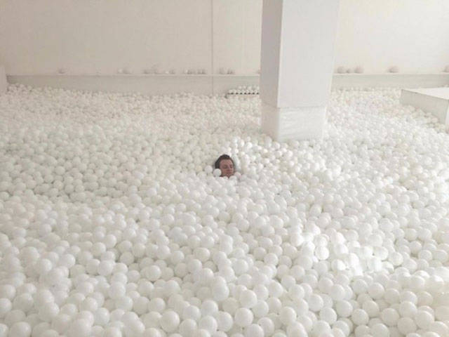 man sitting in a bunch of white balls