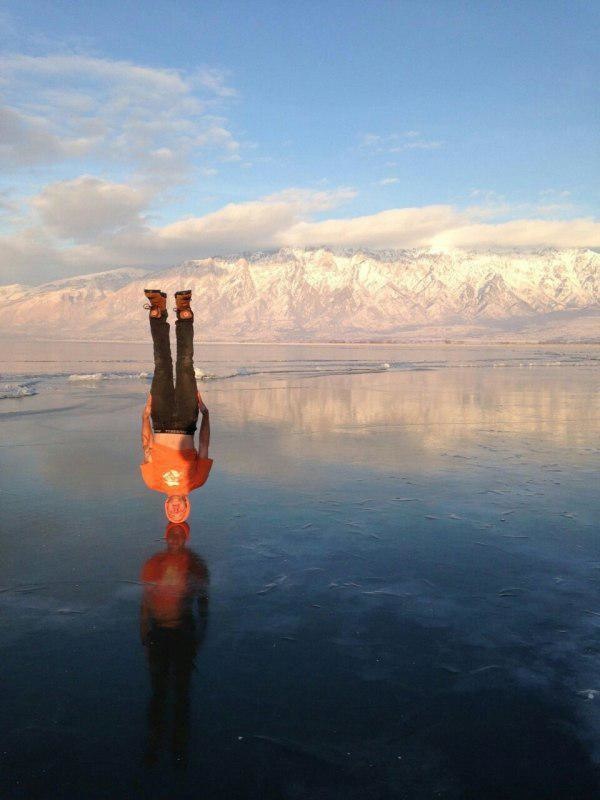 A man achieving a headstand on a frozen lake.