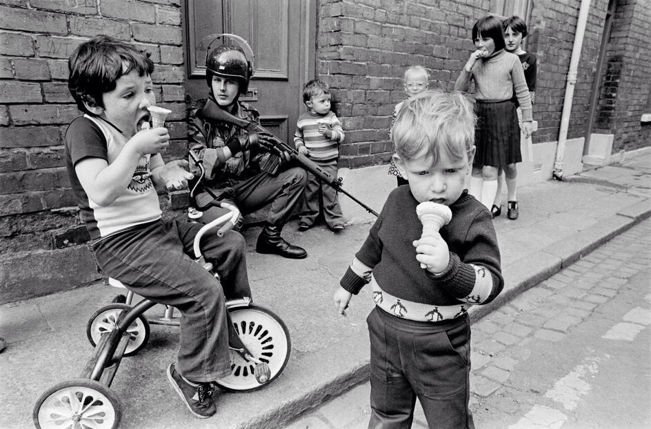1979: Children enjoy their ice cream cones as soldiers patrol the streets of Londonderry, or Derry, a city in Northern Ireland.