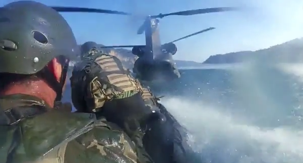 Chinook landing on a lake to retrieve special forces on a zodiac