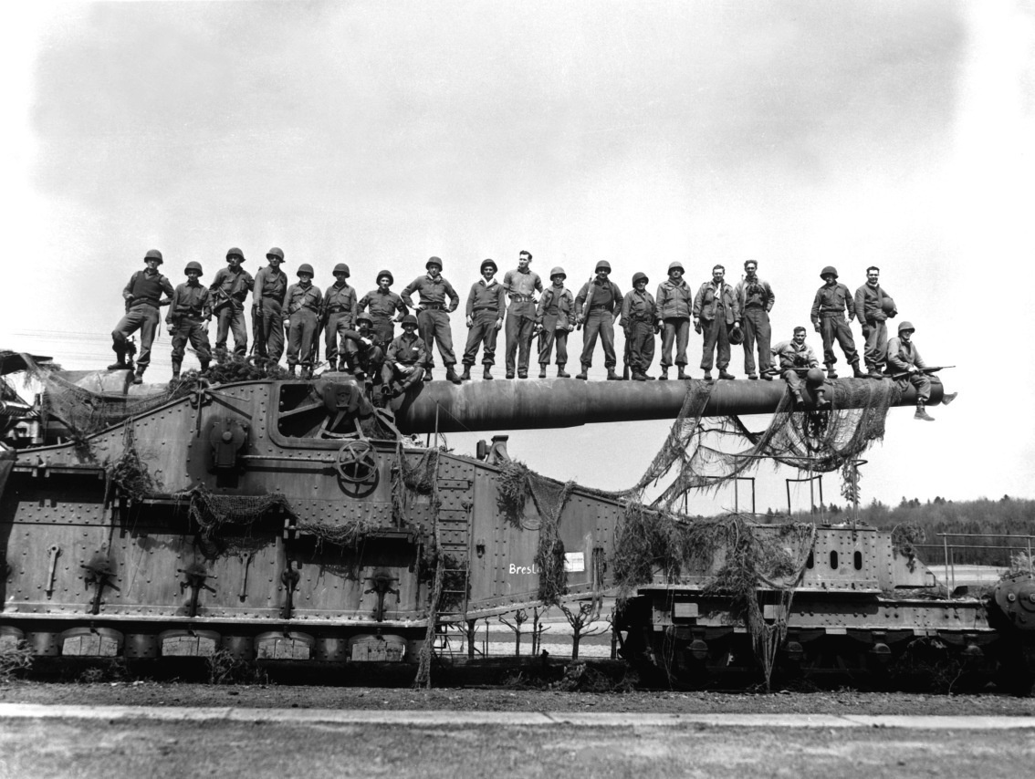 Allied WWII soldiers standing on a captured Schwerer Gustav railway siege gun.