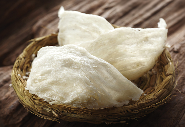 Birds nest soup is made from the nest of a few particular types of swiftlets. But don't picture, as most do, a nest made of twigs, grass, and mud—this nest is composed entirely of the bird's saliva. Yum!

The saliva in question has a glue-like, stringy consistency, and is a mucoglycoprotein (a protein coupled with a carbohydrate). It contains high levels of calcium, iron, magnesium and potassium. The soup is made by soaking or steaming the nest in water, and serving it after it has dissolved into a gelatinous texture. When dry, has a consistency of a petrified sponge. 

Birds nest soup has been considered a delicacy in China since the Tang Dynasty (618-907 AD). Chinese MDs have been prescribing the soup to treat asthma, bronchitis, skin ailments, and to boost energy. It costs a whopping $40-$60 per bowl and $2,000 per kilo. Eat up!