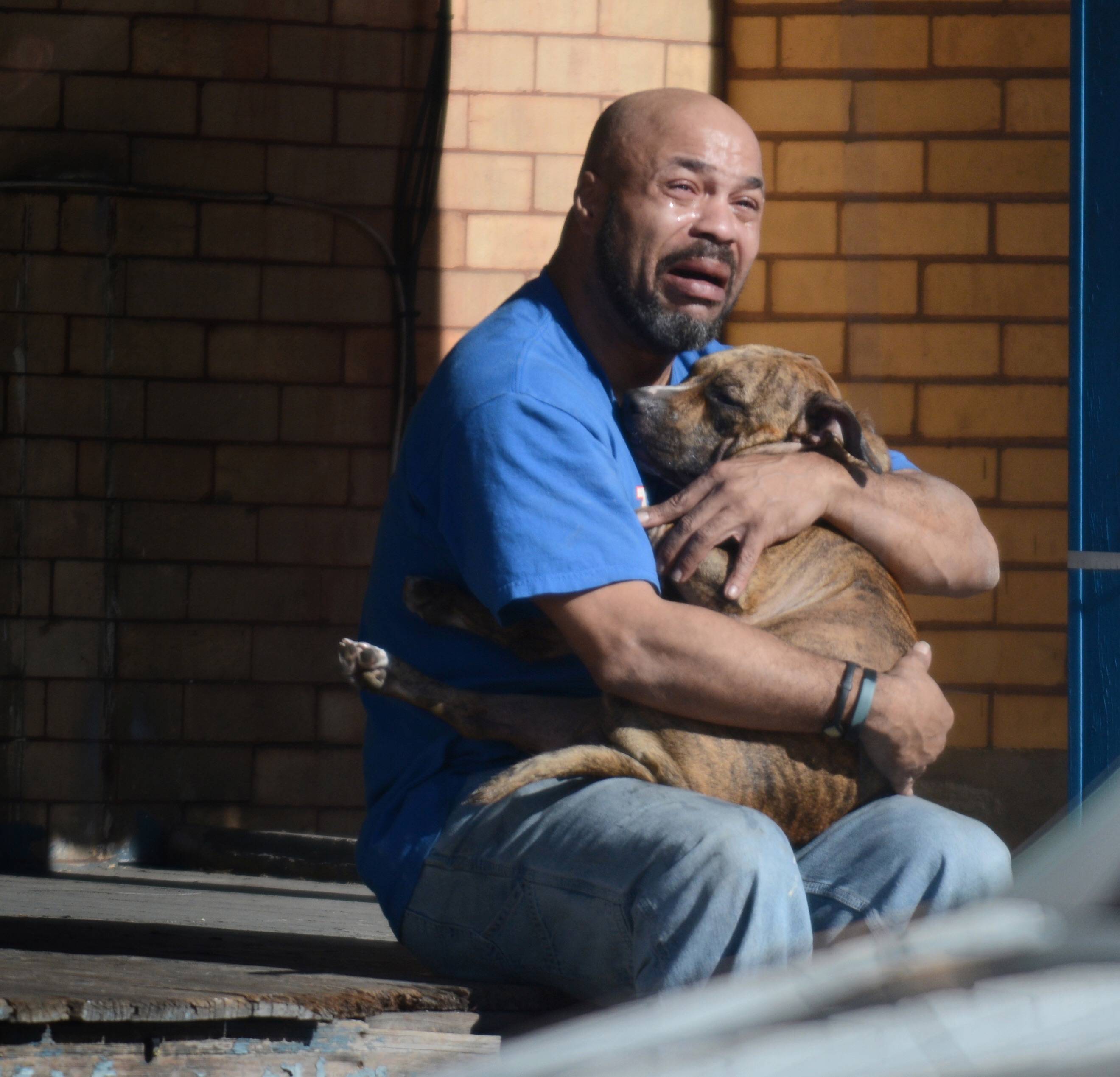 Man holds his dog that passed away from smoke inhalation in a house fire.