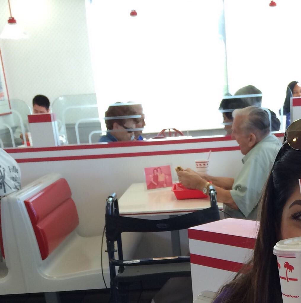 Old man at an In-N-Out burger eating with a picture of his wife.