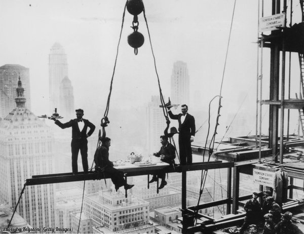 Two waiters serve steel workers lunch on a girder above the Waldorf-Astoria Hotel in 1930s NYC.