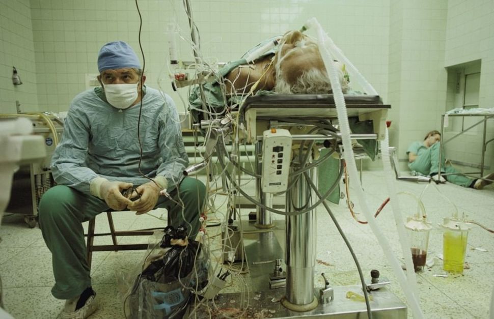 Dr. Religa monitors his patient’s vitals after a 23 hour long heart transplant surgery. His assistant is sleeping in the corner.