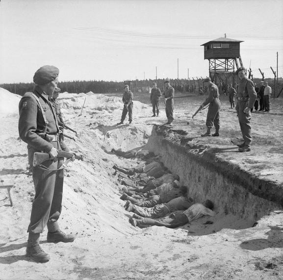 Taken during the liberation of the Bergen-Belsen concentration camp, German SS guards, exhausted from their forced labour clearing the bodies of the dead, are allowed a brief rest by British soldiers but are forced to take it by lying face down in one of the empty mass graves 1945