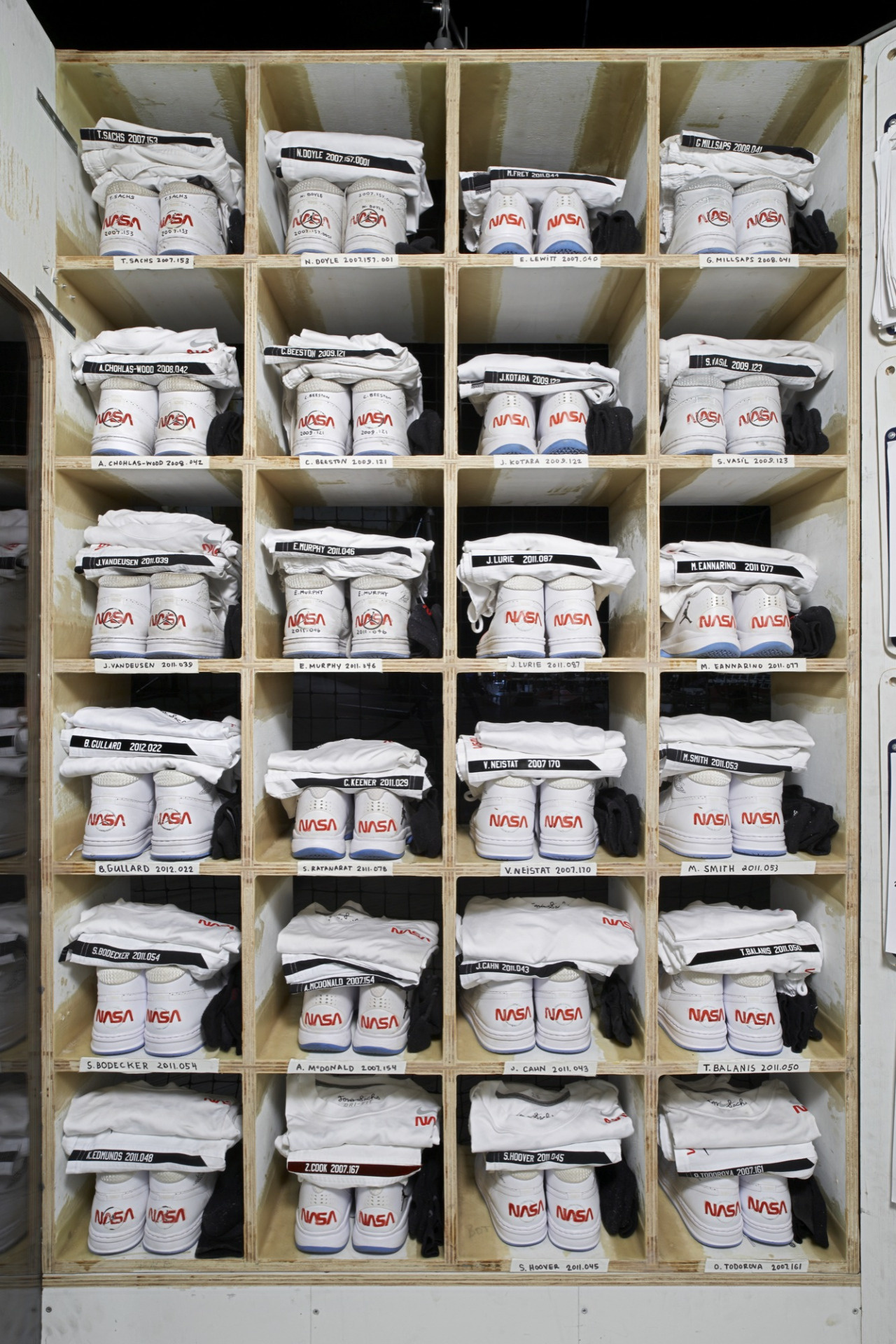 A cubby filled with NASA shoes and shirts.