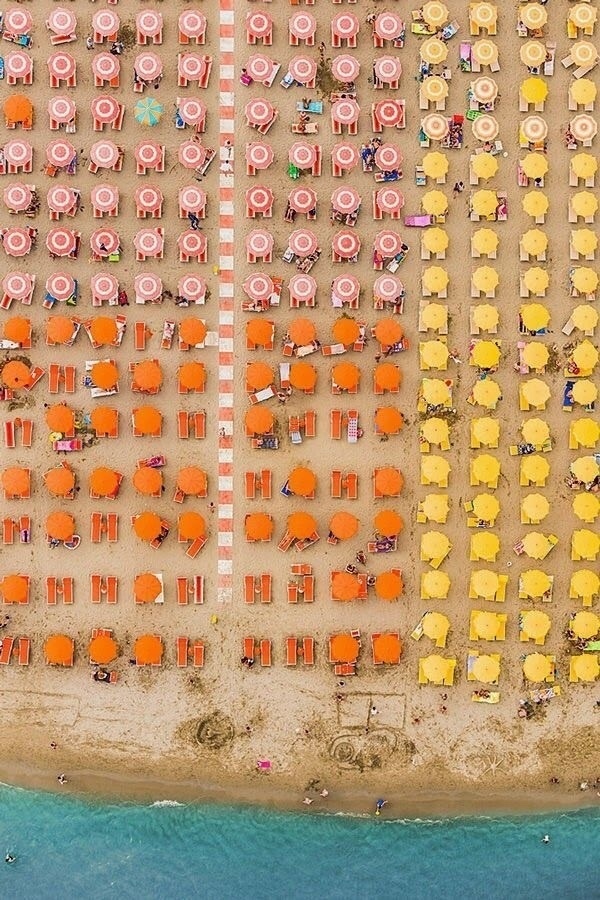 A colorful array of beach umbrellas lined up towards the shore.