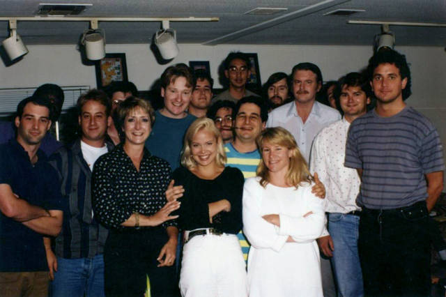 The Simpsons writing room, 1992 

Back row, left to right: Mike Mendel, Colin ABV Lewis (partial), Jeff Goldstein, Al Jean (partial),Conan O’Brien, Bill Oakley, Josh Weinstein, Mike Reiss, Ken Tsumara, George Meyer, John Swartzwelder, Jon Vitti (partial), CJ Gibson and David M. Stern. Front row, left to right: Dee Capelli, Lona Williams and Unknown.