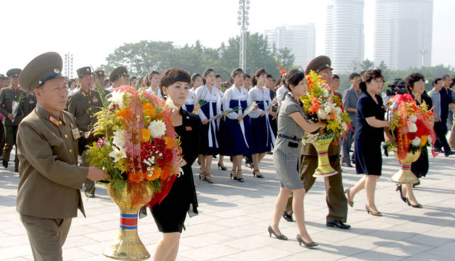 Here, mourners place blower baskets at statue memorials for deceased leaders Kim Il Sung and Kim Jong Il.