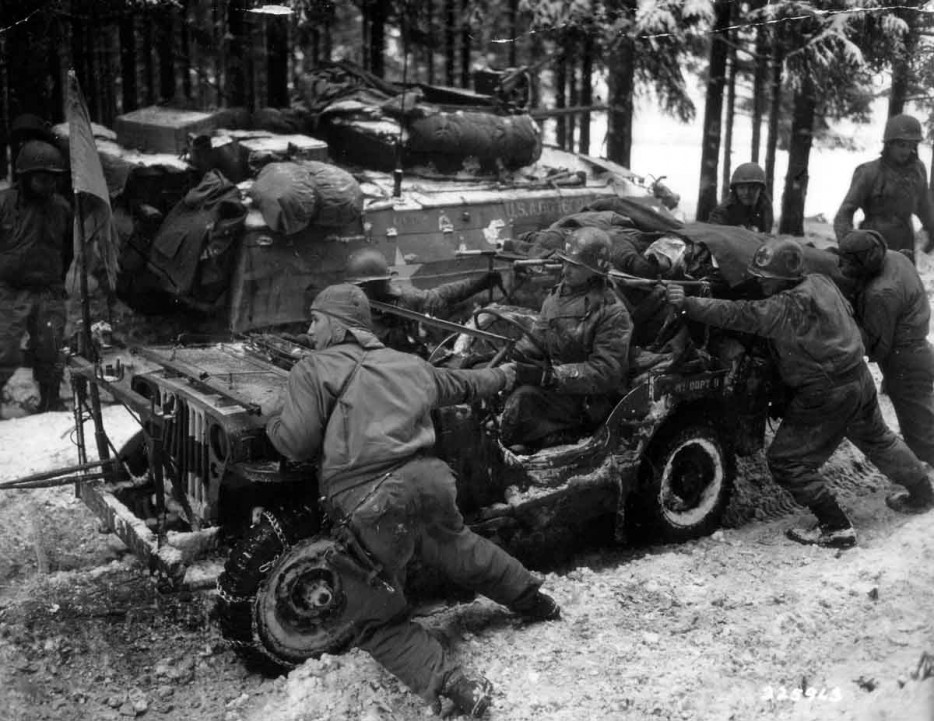 American soldiers of the 4th Armored Division push a trapped car carrying two seriously wounded German soldiers. [World War II, 26 January, 1945]