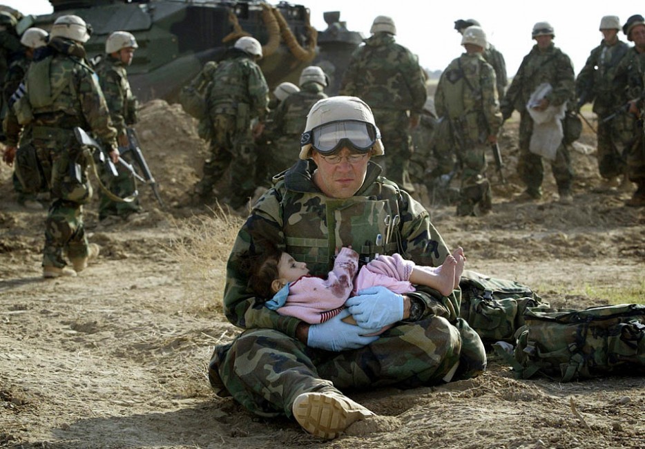 U.S. Navy Hospital Corpsman Richard Barnett holds a child after she was separated from her family during a firefight. [Iraq War, 2003]