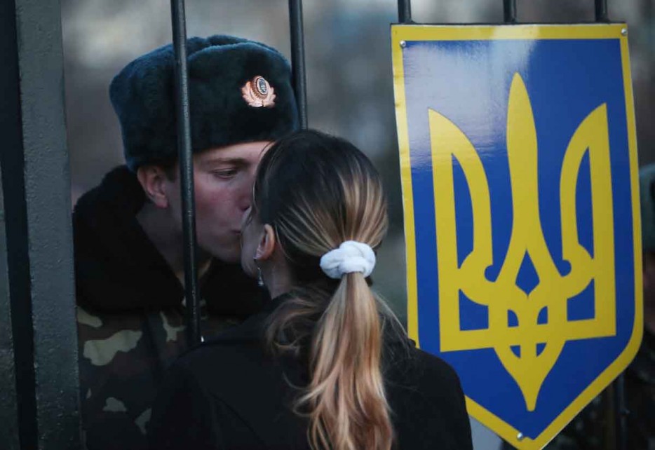 A Ukrainian soldier kisses his girlfriend through the gate of a base surrounded by pro-Russian militants [2014]