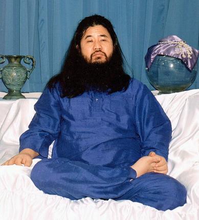 Japanese cult leader Shoko Asahara dressed in blue and sitting with legs crossed