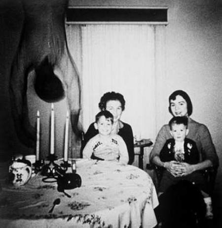 The Cooper family, grandmother, mother, and two sons, posed for this photo only to find out later that someone else, a ghost, was in that room that day. Although the original photo cannot be sourced at this time, it is believed to have been digitally altered.