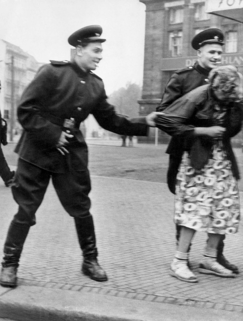 Soviet soldiers openly sexually harass a German woman in Leipzig, 1945.
Soviet soldiers openly sexually harass a passing German woman near the West Hall section of the Leipzig Hauptbahnhof central railway terminus. As Allied troops entered and occupied German territory during the later stages of the war, mass rapes took place both in connection with combat operations and during the subsequent occupation.
The victims not only bore the brunt of revenge for Wehrmacht crimes, they also represented an atavistic target as old as war itself. Rape is the act of a conqueror, the historian Susan Brownmiller observed, aimed at the “bodies of the defeated enemy’s women” to emphasize his victory.
Most historians agree, although the issue is contentious, that the majority of the sexual assaults on German female civilians were committed in the Soviet occupation zone; estimates of the numbers of German women raped by Soviet soldiers have ranged up to 2 million. In many cases women were the victims of repeated rapes, some as many as 60 to 70 times.
At least 100,000 women are believed to have been raped in Berlin, based on surging abortion rates in the following months and contemporary hospital reports, with an estimated 10,000 women dying in the aftermath. Female deaths in connection with sexual assaults in Germany, overall, are estimated at 240,000. War historians have described it as the “greatest phenomenon of mass rape in history”, and have concluded that at least 1.4 million women were raped in East Prussia, Pomerania and Silesia alone.
The novelist Vasily Grossman, a war correspondent attached to the invading Red Army, soon discovered that rape victims were not just Germans. Polish women also suffered. So did young Russian, Belorussian and Ukrainian women who had been sent back to Germany by the Wehrmacht for slave labour. “Liberated Soviet girls quite often complain that our soldiers rape them”, he noted. “One girl said to me in tears: He was an old man, older than my father”.