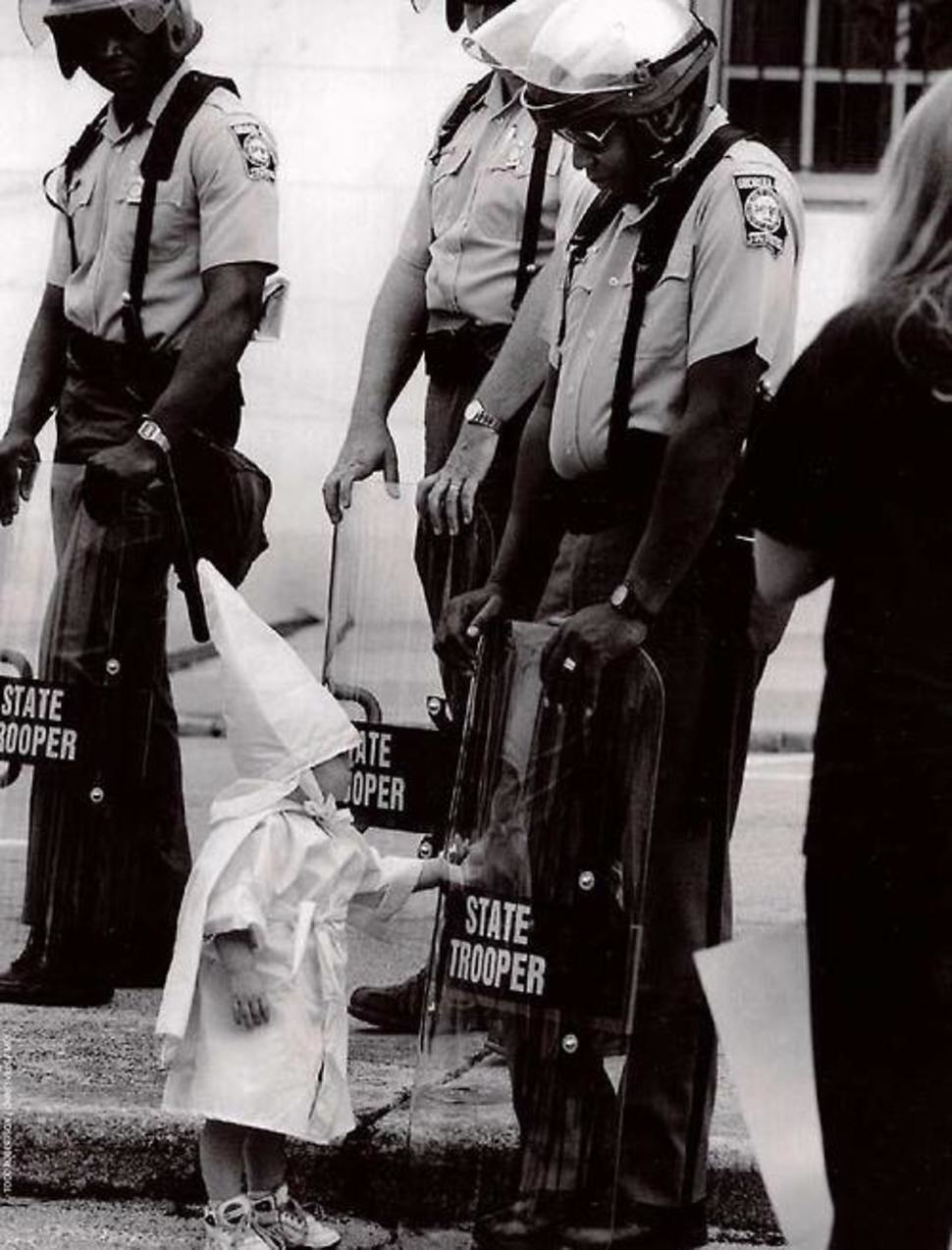 A KKK member's child touching his reflection in an African American police officer's shield in 1992.