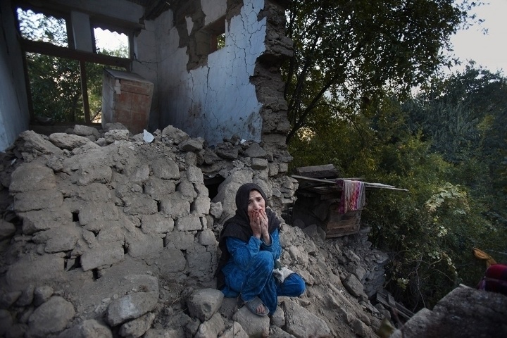 A Pakistani woman grieving in front of what's left of her home after she lost two of her grandsons to an earthquake that killed more than 380 people in the region.