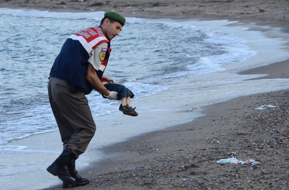 A Turkish police officer carrying the lifeless body of a Syrian child from a boat of refugees that sank while trying to get to the Greek island of Kos.