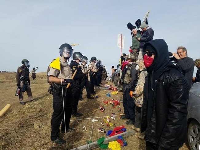 Armed soldiers and law enforcement officers standing in a line to prevent the Dakota Access pipeline protesters from blocking the construction on private land.