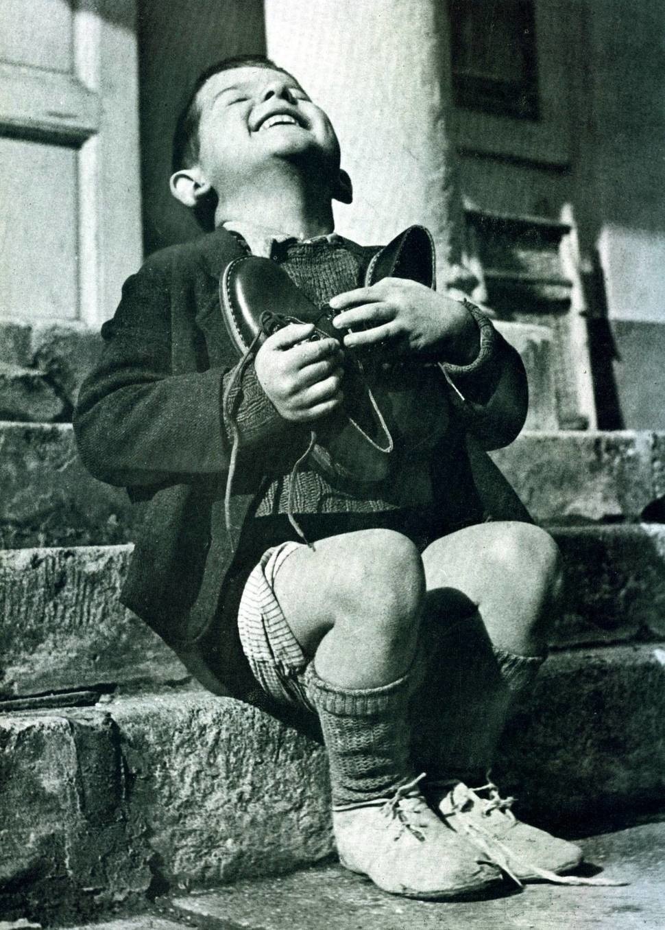 A 6 year old orphan, Werfel, being given his first pair of new shoes by the American Red Cross in 1946.