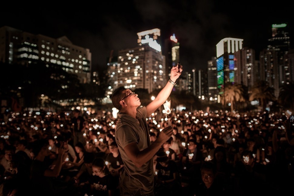 A man taking a photo in Tiananmen Square amongst people attending a candlelight vigil in Hong Kong to commemorate China's 1989 crackdown.