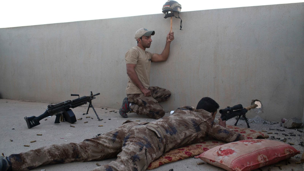 An Iraqi special forces soldier puts up a helmet as a decoy as a sniper gets ready to fire on Islamic State positions